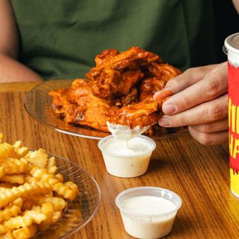 Wing Shack 35th Ave - A saucy traditional wing being dipped in Wing Shack's famous ranch - Chicken Wings Near Me - Greeley, Colorado