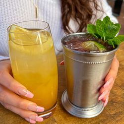 Dog Haus - A Passion Fruit Spritz and an Irish Mule-style drink with fresh mint sit on a table, highlighting the refreshing, handcrafted...