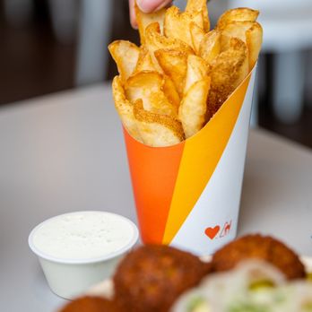 Naf Naf Grill - a hand picking up some fries - Falafel Near Me - Eagan, Minnesota
