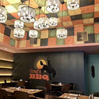 Greg's BBQ - Dining area at Greg's BBQ features a colorful, patterned ceiling, hanging pendant lights, and a dark wall with the restaurant's logo. - Barbeque Near Me - Belen, New Mexico