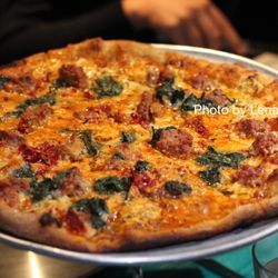 Nick's Restaurant and Bar - Local Sausage Pizza ($19.50) - Italian sausage, peperonata, spicy Calabrese chiles, fontina cheese, herbed goat cheese, spinach