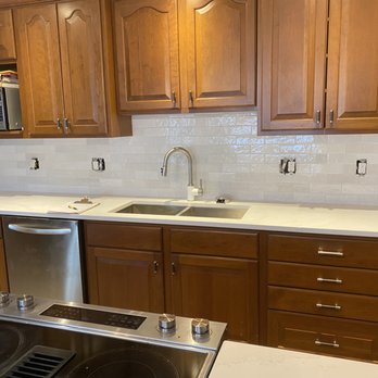 Marty Champagne - a kitchen with white countertops and wood cabinets - Flooring Near Me Marty Champagne - a kitchen with white countertops and wood cabinets - Flooring Near Me