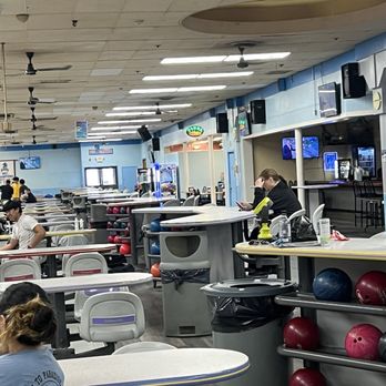 Bowler City - An indoor bowling alley features seating areas, bowling balls on racks, and people engaged in activities like using their phones. - Bowling Near Me - Hackensack, New Jersey