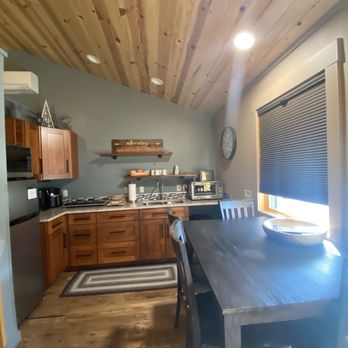 Solitude Cabins - Kitchen with a toaster over and cooktop, keuric with coffee pods, refrigerator and microwave, seating for 4. - Hotels Near Me - Estes Park, Colorado Solitude Cabins - Kitchen with a toaster over and cooktop, keuric with coffee pods, refrigerator and microwave, seating for 4. - Hotels Near Me - Estes Park, Colorado