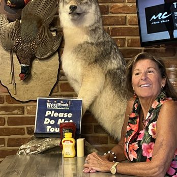 Westwoods Lodge Pub & Grill and Big Timber Bourbon Bar - a woman sitting at a table with a stuffed wolf - American Near Me - Springfield, Illinois