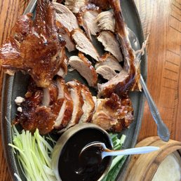 Half Peking duck with hoisin sauce, green onions, white onions, and cucumber.