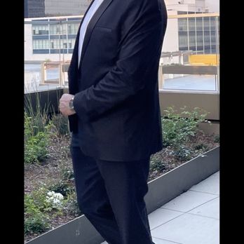 Viera Alteration - A man dressed in a tuxedo with sunglasses stands on a balcony with city buildings behind him, possibly attending a formal event. - Sewing & Alterations Near Me - Rockledge, Florida