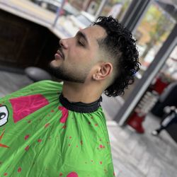 Low taper fade con rizos arriba y barba definida.