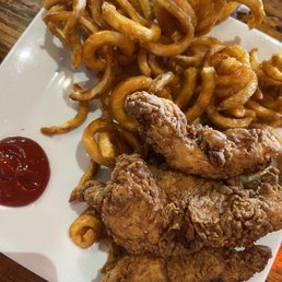 Chicken tenders - A plate of fried chicken tenders served with curly fries and a side of ketchup, presented on a white dish at a restaurant.