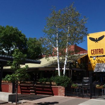 Centro Mexican Kitchen - This fun & lively restaurant on Pearl Street creates fresh and festive Mexican cuisine for brunch, lunch, happy hour, & dinner. - A building with a yellow sign displaying the name 'Centro' and a black eagle logo is visible on Pearl Street. The restaurant has outdoor seating with tables and umbrellas, and is surrounded by trees and a clear blue sky. The storefront includes a covered patio area and decorative elements along the sidewalk. - Mexican Near Me - Boulder, Colorado