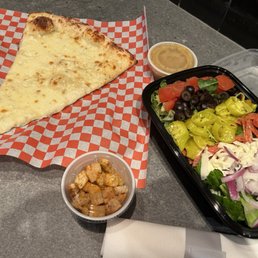 Slice of white pizza and Italian salad.
