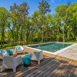 Venture Custom Pools - Escape to your own private retreat with this stunning natural pool featuring clean lines, travertine decking, and warm wood accents.