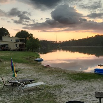 Emerald Lake Naturist Resort - A gorgeous sky backdrops this view from the beach. The yellow building to the left is the Lake House. - Resorts Near Me - Porter, Texas