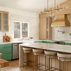Tayara Home - Kitchen interior design in colors, natural wood and brass rangehood.