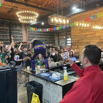 Hook Hall - A performer in purple and yellow sportswear is on a bar counter, with a crowd of people cheering and taking photos at an indoor venue. - Venues & Event Spaces Near Me - Washington, DC, District of Columbia