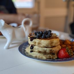 a stack of pancakes with blueberries and strawberries
