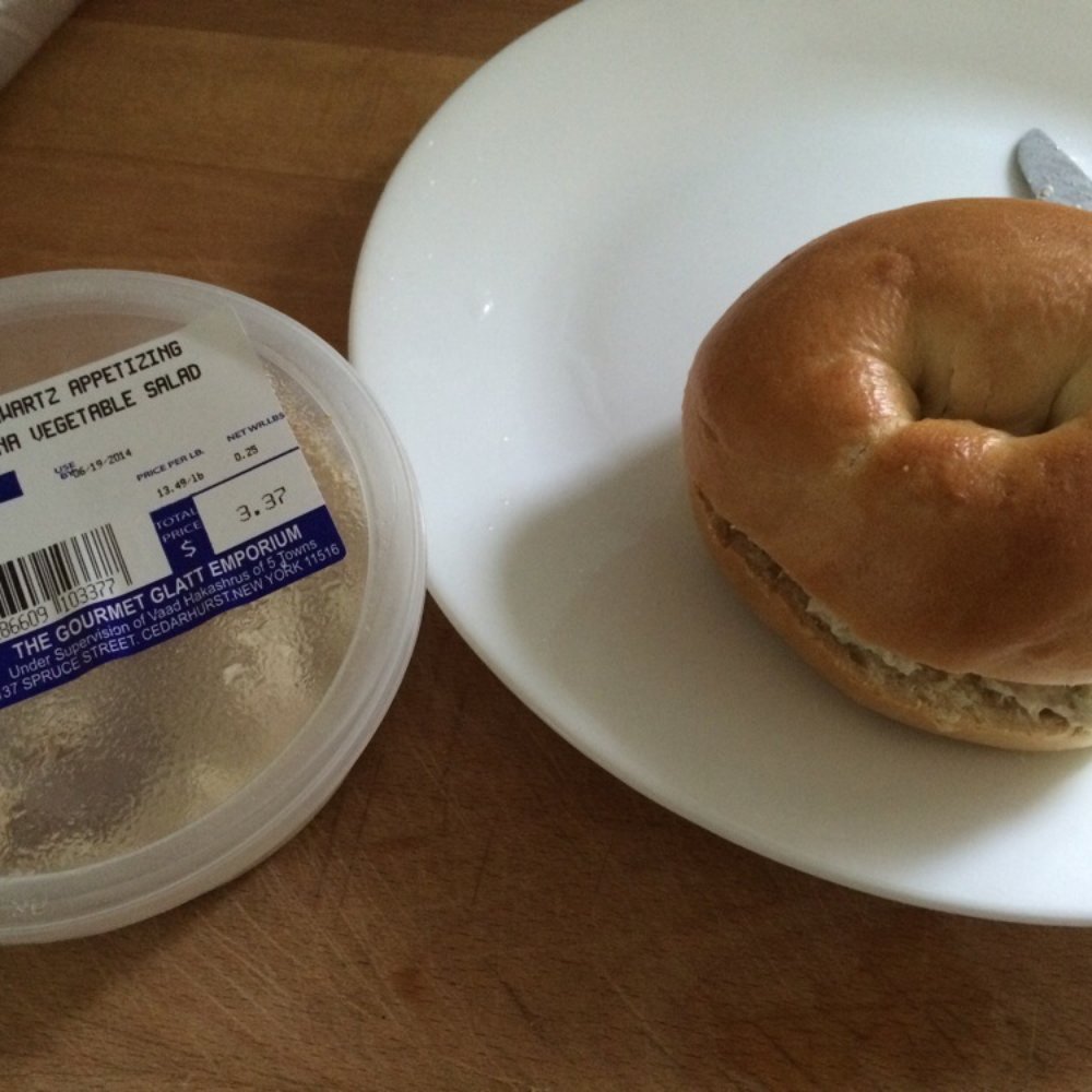 a bagel on a plate next to a plastic container a bagel on a plate next to a plastic container