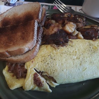 Mahaney’s - CBH omelet, well-done HFs - A breakfast plate includes two slices of toasted bread, a folded omelet seasoned with black pepper, and cooked meat pieces, likely bacon or ham. The meal is served on a green ceramic plate, with a fork and a white mug visible in the background, indicating a casual dining setting. - Breakfast & Brunch Near Me - Windsor, Connecticut