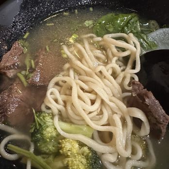 Fun Noodle Bar - 26. Beef Noodle Soup in Clear Broth - A bowl of beef noodle soup featuring broth, thick noodles, beef slices, and green vegetables, served in a black bowl. - Chinese Near Me - Santa Fe, New Mexico