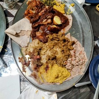 Aster's Ethiopian Restaurant - (bad photo)The bottom is the lentils, next up is the lamb stew, up is the national dish of Ethiopia, and there's the collared greens on top. - Ethiopian Near Me - Austin, Texas