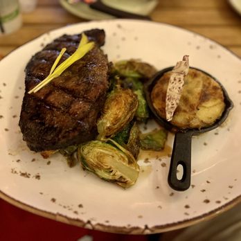 Tikis Grill & Bar - Pulehu 14oz NY Steak Tarragon scalloped potato skillet, crispy Brussels sprouts, three pepper butter. - Seafood Near Me - Honolulu, Hawaii Tikis Grill & Bar - Pulehu 14oz NY Steak Tarragon scalloped potato skillet, crispy Brussels sprouts, three pepper butter. - Seafood Near Me - Honolulu, Hawaii