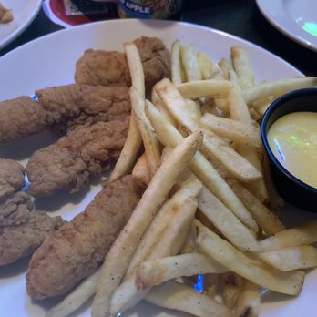 Applebee's Grill + Bar - Chicken Tenders Plate - Fried chicken tenders with French fries and a side of dipping sauce on a white plate at Applebee's Grill + Bar. - Sports Bars Near Me - Lima, Ohio