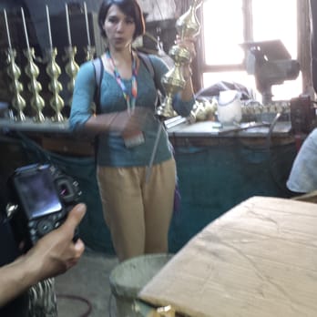 Culinary Backstreets - Our lovely tour guide showing the bronzesmith's work, a partially completed hookah - Food Tours Near Me