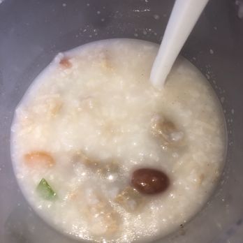 Rongwang Restaurant - Congee - A bowl of congee with ingredients like mushrooms and vegetables, with milk being poured into it. - Noodles Near Me - Flushing, New York