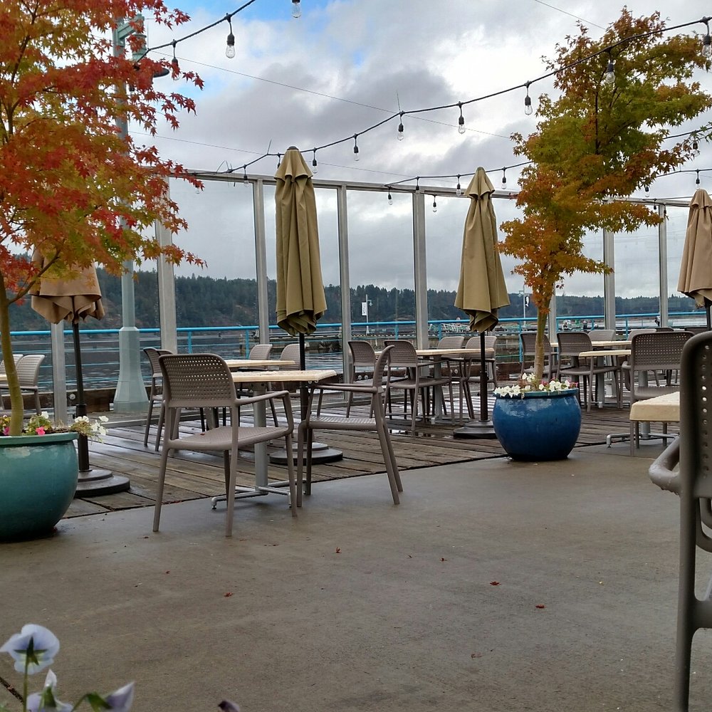 tables and chairs on a patio overlooking a lake
