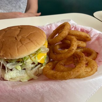 Midway Oh-Boy Restaurant - OH Boy Sandwich - A burger with lettuce, cheese, and a soft bun is served alongside a pile of onion rings on a pink paper-lined tray. - American Near Me - Elyria, Ohio