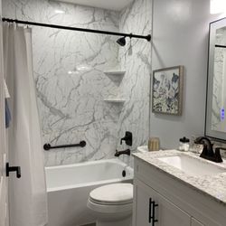 Improveit Home Remodeling - Updated hall bathroom with Calcutta marble walls and tub-shower combo. See the full Before & After at improveitusa.com/projects.