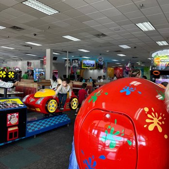 Chuck E. Cheese - a large red ball in a toy store - Kids are playing on arcade rides and games in the indoor play area of Chuck E. Cheese in Skokie, Illinois. - Pizza Near Me - Skokie, Illinois