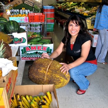 Mithepheap Market - Yun, store owner, cutting up a jackfruit by the front entrance - International Grocery Near Me - Oakland, California Mithepheap Market - Yun, store owner, cutting up a jackfruit by the front entrance - International Grocery Near Me - Oakland, California