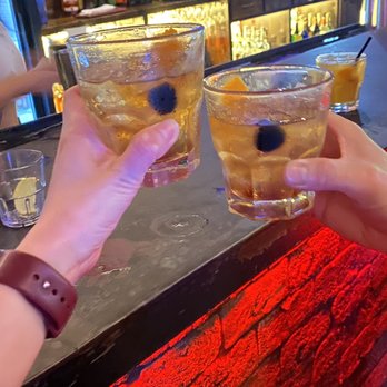 Two Bucks - two people toasting at a bar - Cocktail Bars Near Me - Austin, Texas