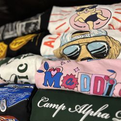 The Embroidery Shop - Assortment of screenprinted t-shirts, baby tees, oversized tees, and more. All projects completed at the Embroidery Shop.