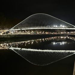Puente Zubizuri - Calatrava bridge at night, reflected in the river.