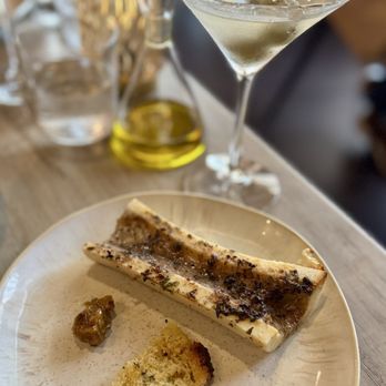 Ember & Cork - A martini cocktail in a classic glass with a garnish, alongside a plate with cheese, bread, and a condiment, on a wooden table. - Seafood Near Me - Schenectady, New York
