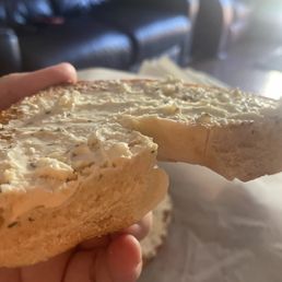 a hand holding a bagel with a bite taken out of it a hand holding a bagel with a bite taken out of it