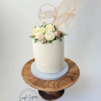 Simple Sugars - a white cake with flowers and a happy birthday sign - Desserts Near Me