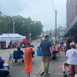 a crowd of people sitting and standing on the sidewalk