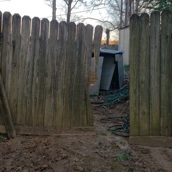 Solid As A Rock - a wooden fence with a doghouse in the background - Landscaping Near Me - Little Rock, Arkansas