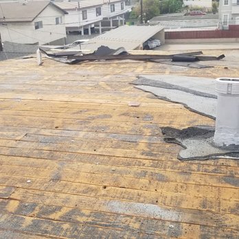 Bonded Roofing - Tear off day 1 - A rooftop with worn, discolored shingles and visible damage, including missing sections and a vent pipe. - Roofing Near Me - Long Beach, California