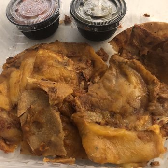 Chili's - Fried chicken with golden, crispy skin and visible seasoning, accompanied by two small containers of dark sauce, and a piece of cornbread in a clear plastic takeout container. The food appears freshly prepared and ready for pickup or delivery. - Bars Near Me - Lone Tree, Colorado