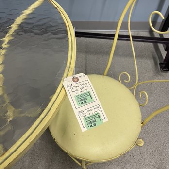 St Vincent DePaul - A yellow patio table and matching chair with a glass top and metal frame, displayed in a store with price tags attached. - Thrift Stores Near Me - Milwaukee, Wisconsin