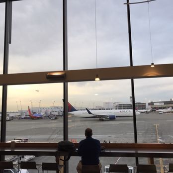 Club International - a man looking out the window at an airport - Airport Lounges Near Me - Seattle, Washington Club International - a man looking out the window at an airport - Airport Lounges Near Me - Seattle, Washington
