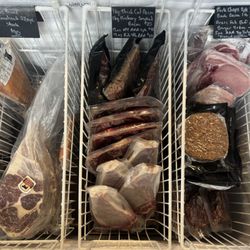 Display freezer featuring 50oz prime tomahawk ribeye, rib steaks, AAA NY steaks, double smoked bacon, pork chops, grass fed burgers