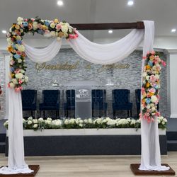 Tlapazola Event Rentals - Elegant floral wedding arch setup with soft draping and ceremony staging for upscale Los Angeles wedding receptions.