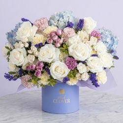 Pink Clover - White roses and blue hydrangea with lavender spray roses, lilac carnations and purple statice.