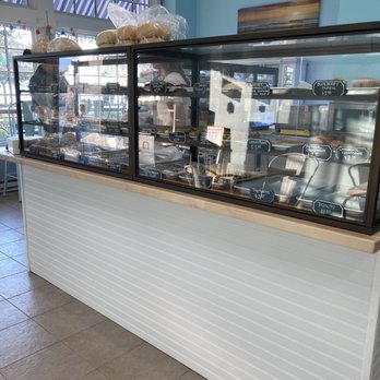 Beach Bum Bakery - A bakery display case showcases various baked goods with handwritten labels, inside a bakery shop with light blue walls and large windows. - Cupcakes Near Me - Pewaukee, Wisconsin