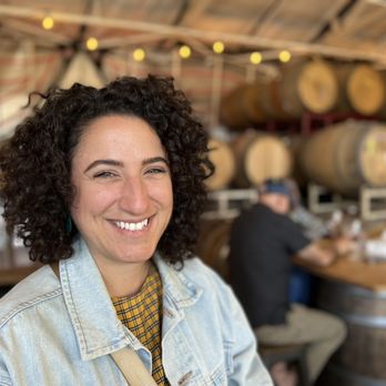 Windchaser Wine - Me enjoying my wine against a backdrop of wine barrels and other people hanging out - Wineries Near Me - Richmond, California Windchaser Wine - Me enjoying my wine against a backdrop of wine barrels and other people hanging out - Wineries Near Me - Richmond, California